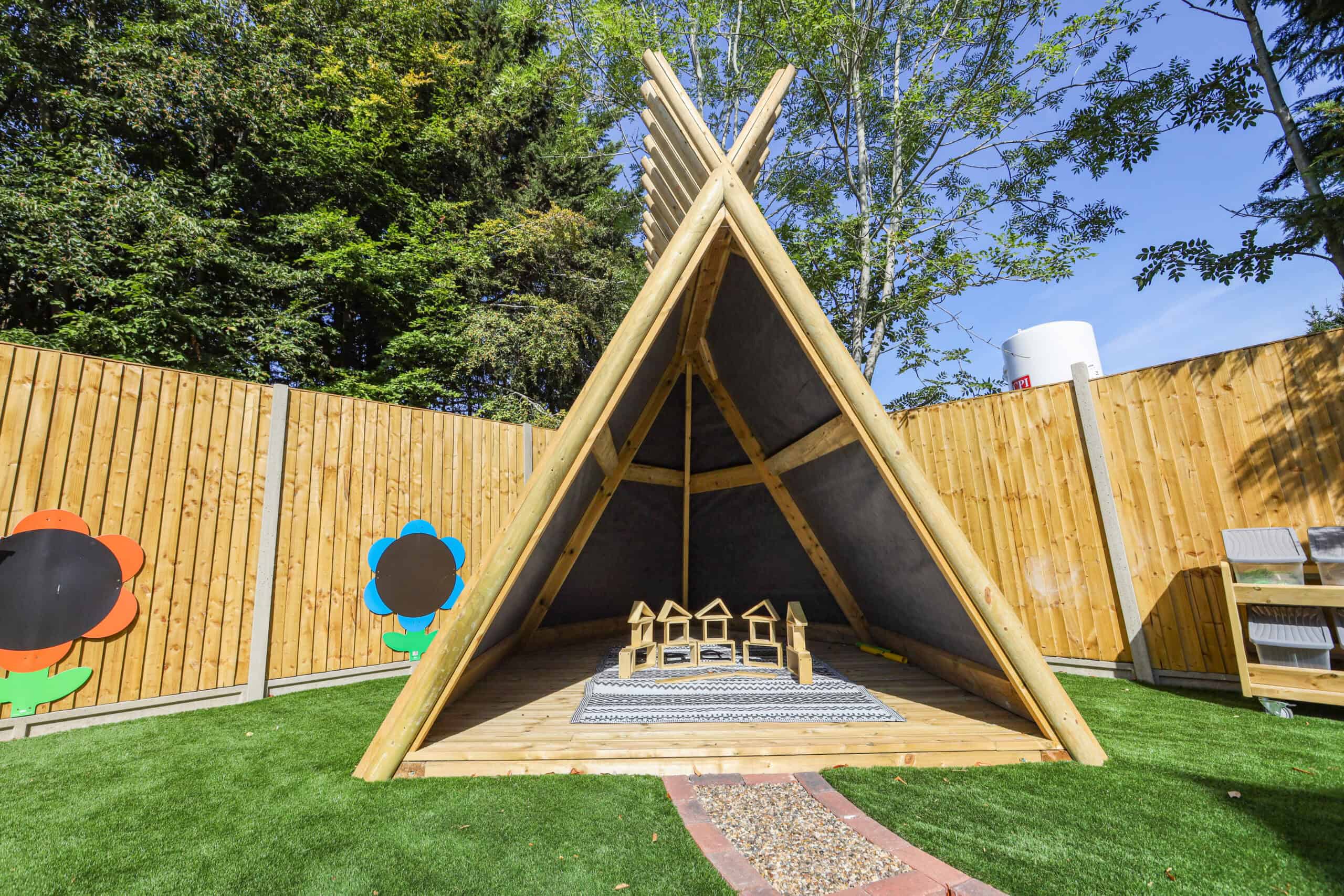 A triangular outdoor play tent with chairs inside at Monkey Puzzle Radlett nursery.