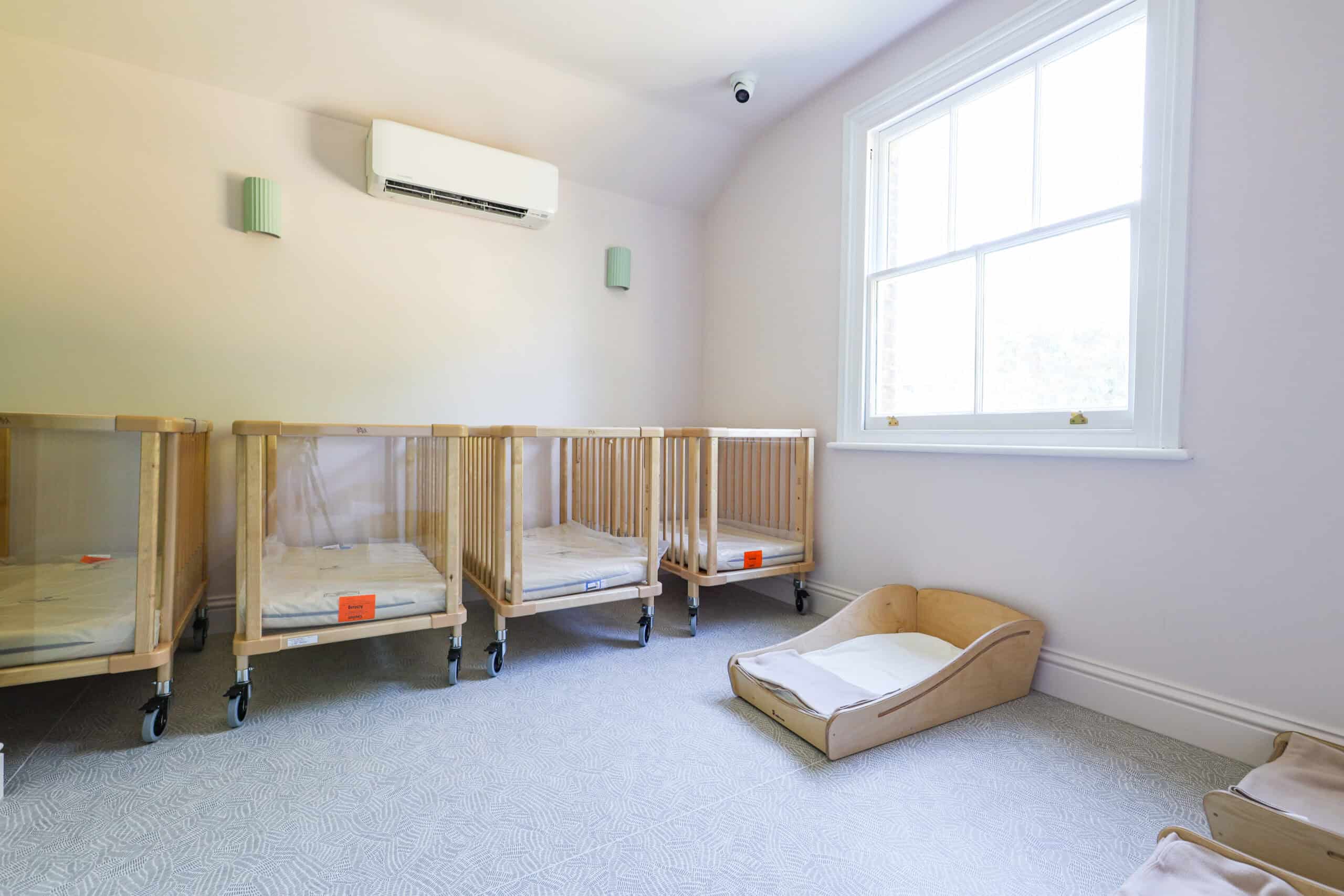 Nursery room with cribs and a cozy corner for children at Monkey Puzzle Radlett.