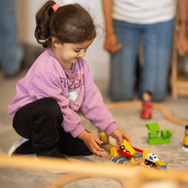 Young girl playing with colorful toy vehicles at Monkey Puzzle Day Nursery Radlett.